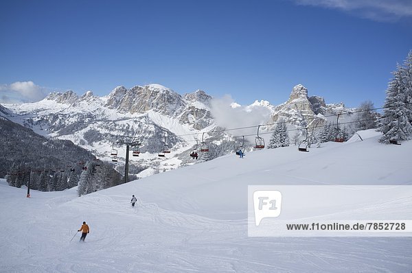 Skiers at the Alta Badia ski resort with Sassongher Mountain in the distance  Dolomites  South Tyrol  Italy  Europe