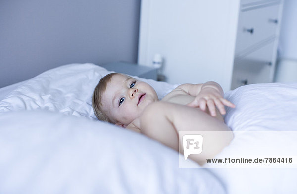 Naked baby lying on bed