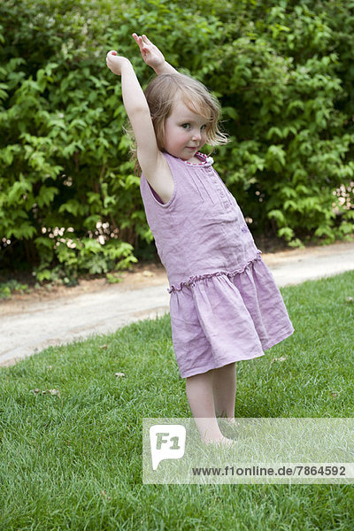 Kleines Mädchen im Freien stehend mit erhobenen Armen