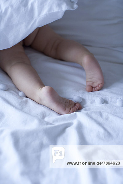 Babys nackte Füße unter der Bettdecke,  abgeschnitten