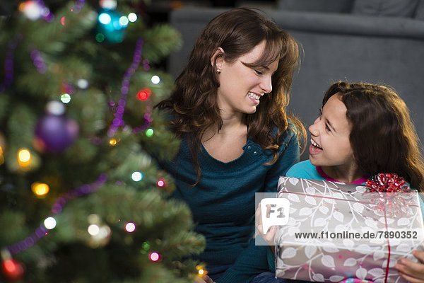 Hispanic mother and daughter opening Christmas presents