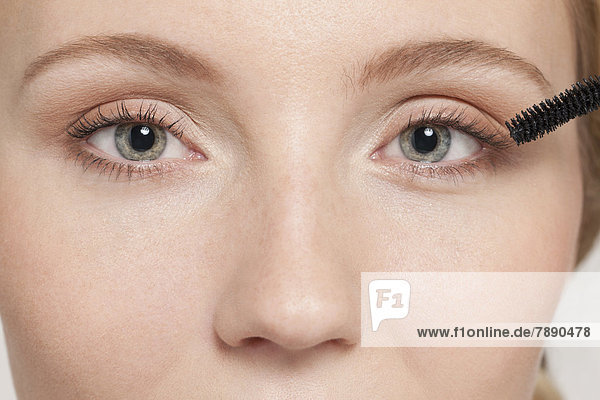 Caucasian woman applying mascara