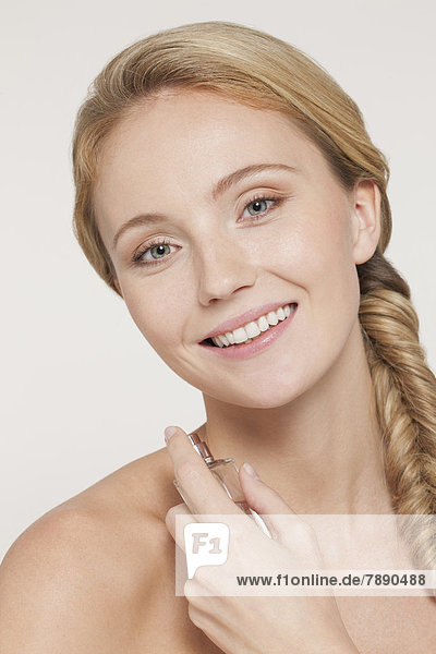 Nude Caucasian woman spraying perfume