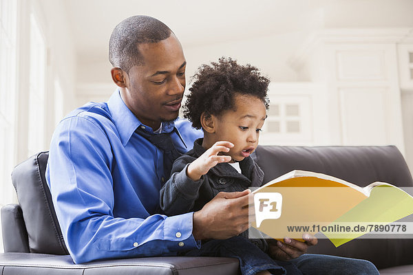Father and son reading on sofa