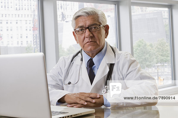 Hispanic doctor using laptop in office