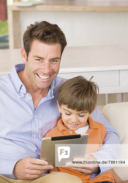 Vater und Sohn schauen in Tablet PC