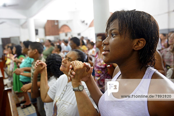 Worshippers holding each other's hands and praying  Catholic mass in a slum or favela *** NO PUBLICATION IN BRAZIL ***
