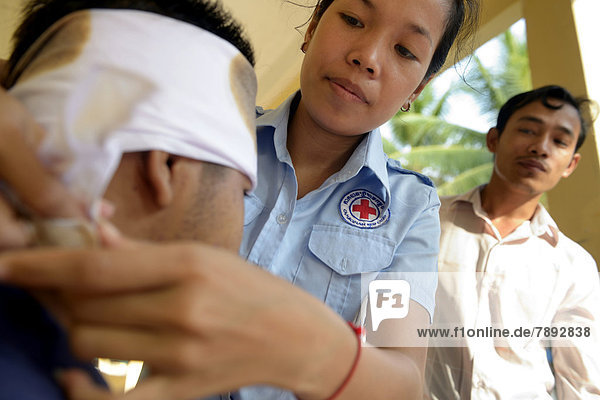 Young woman applying a head bandage  training of young people from the community to become first aid workers by the Red Cross