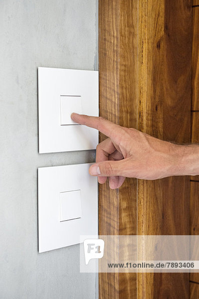 Close-up of a person's hand pressing a light switch
