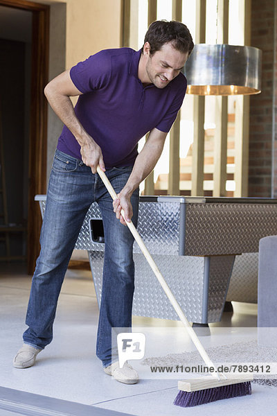 Mann reinigt den Boden mit einem Wischmopp