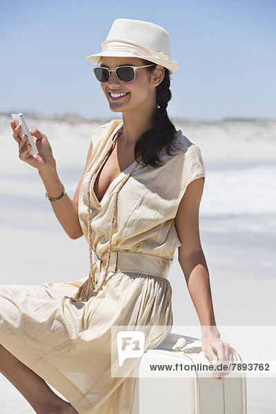 Schöne Frau SMS auf einem Handy am Strand