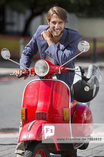 Portrait of a man sitting on a scooter and smiling