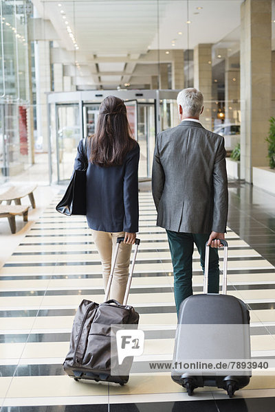 Business couple pulling suitcases in a hotel lobby