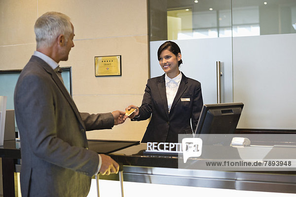 Businessman paying with a credit card at the hotel reception counter