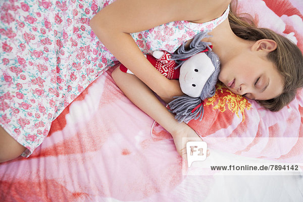 Girl sleeping on the bed with a rag doll