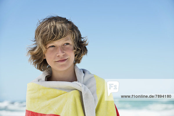 Junge in ein Handtuch gewickelt am Strand