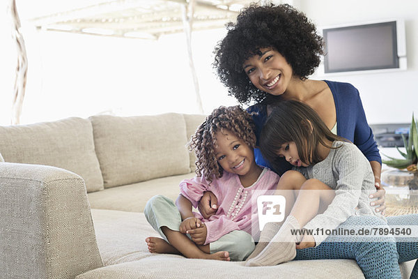 Lächelnde Frau sitzend mit ihren beiden Töchtern
