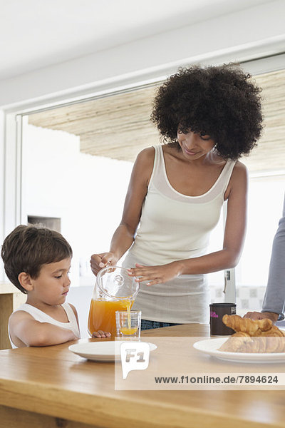 Woman giving orange juice to her son