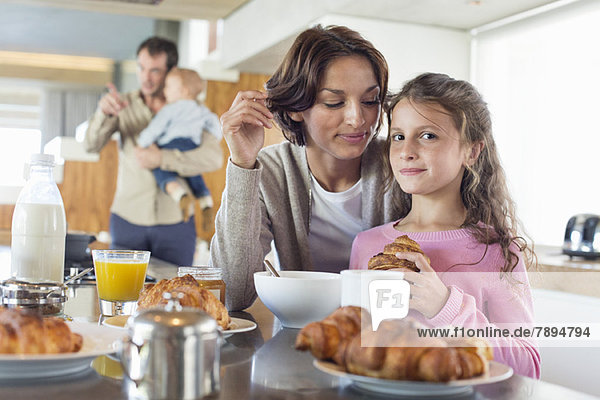 Mädchen frühstückt neben ihrer Mutter an der Küchentheke