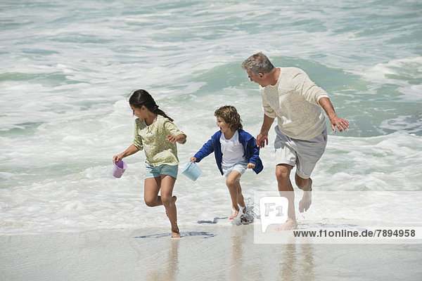 Children playing with their grandfather on the beach