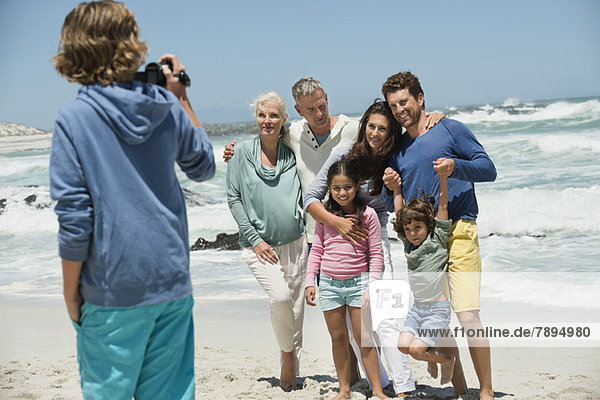 Boy filming his family with a home video camera on the beach