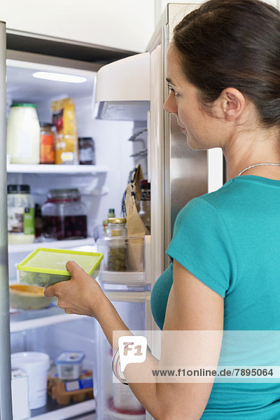 Frau stellt Essen in den Kühlschrank