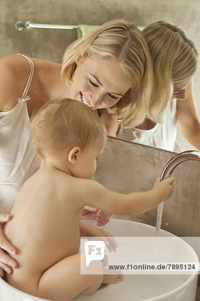 Frau badet ihr Baby in einer Waschschüssel