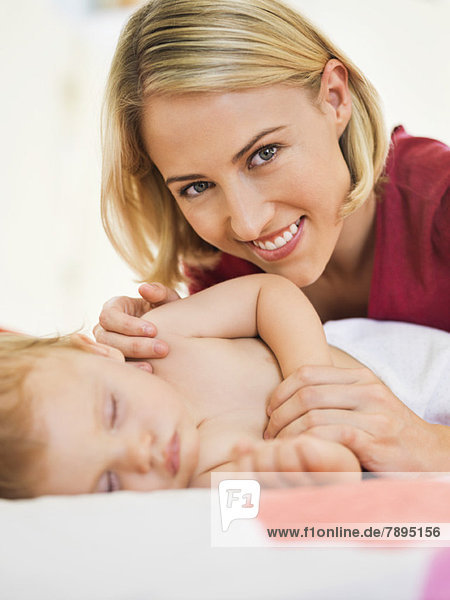 Frau in der Nähe ihres Babys schlafend auf dem Bett