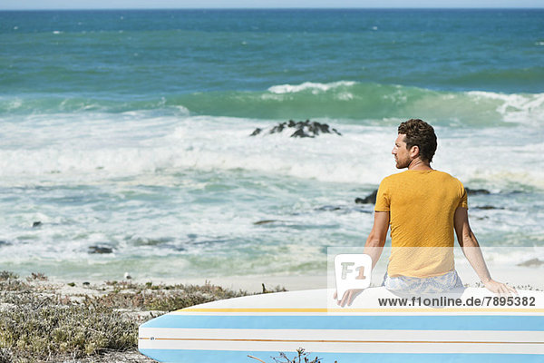 Man sitting on a surfboard on the beach