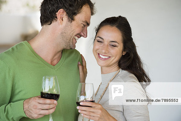 Paar hält Weingläser und lächelt