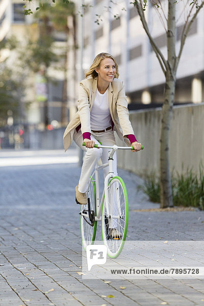 Woman riding a bicycle on a street and smiling