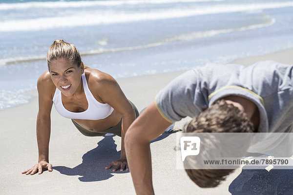 Woman exercising on the beach with her coach