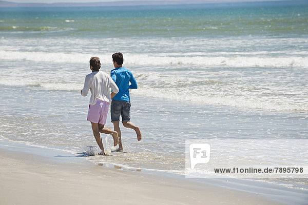 Two men running on the beach