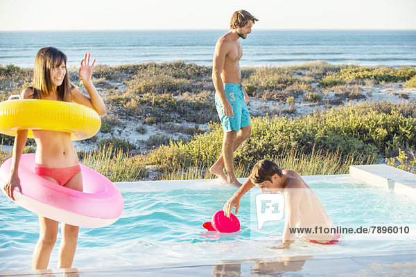 Drei Freunde  die sich an einem Swimmingpool am Strand vergnügen.