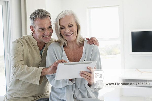 Lächelndes Seniorenpaar mit einem digitalen Tablett
