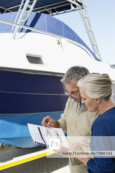 Paar beim Lesen einer Broschüre in der Nähe einer Yacht
