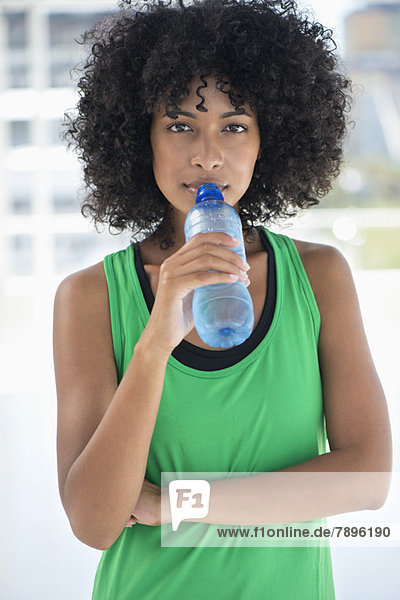Porträt einer Frau  die Wasser aus einer Flasche trinkt
