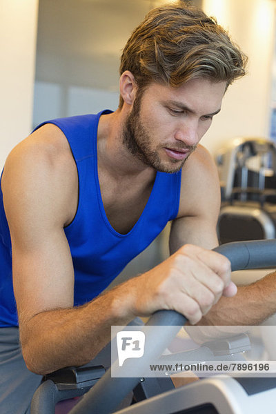 Mann beim Training an einer Maschine im Fitnessstudio