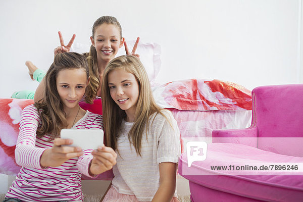 Three girls taking a picture of themselves with a mobile phone at a slumber party
