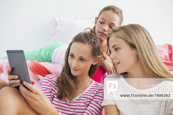Three girls using a digital tablet at a slumber party
