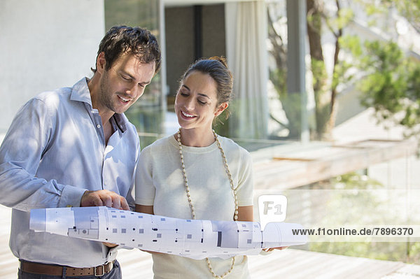 Couple looking at blueprint and smiling