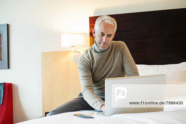 Man using a laptop in a hotel room