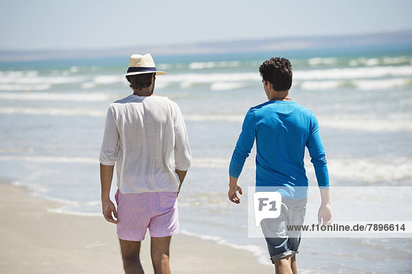 Zwei Männer  die am Strand spazieren gehen.