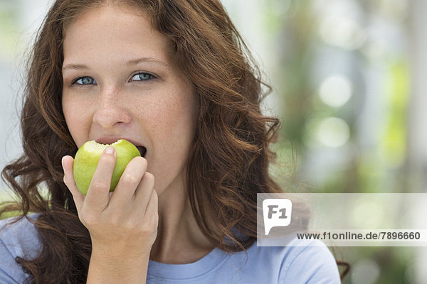 Porträt einer Frau beim Essen eines grünen Apfels