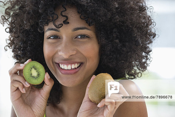 Porträt einer lächelnden Frau mit Kiwifrüchten