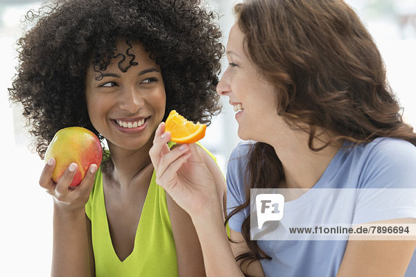 Close-up of two female friends eating fruits