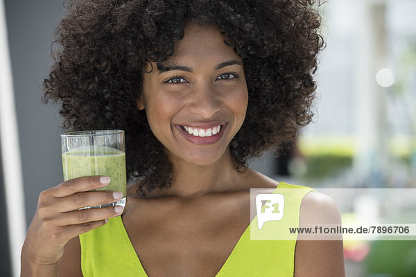 Portrait of a woman holding a glass of kiwi juice
