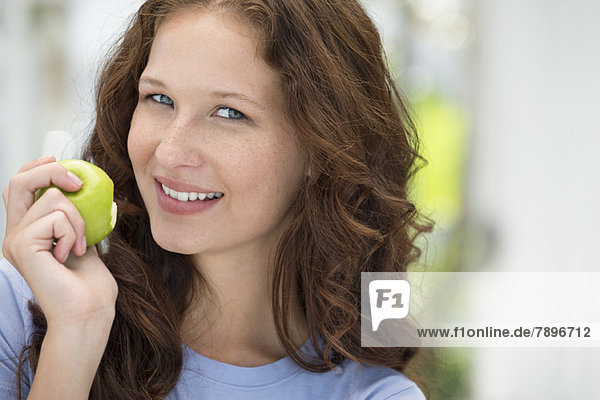 Porträt einer Frau beim Essen eines grünen Apfels