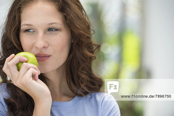 Nahaufnahme einer Frau beim Essen eines grünen Apfels