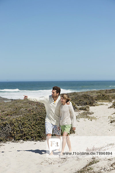Mann  der mit seinem Sohn auf den Strand zeigt